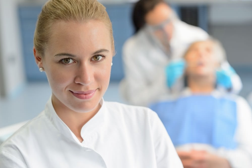 dental assistant with dentist in background Обязанности ассистента стоматолога