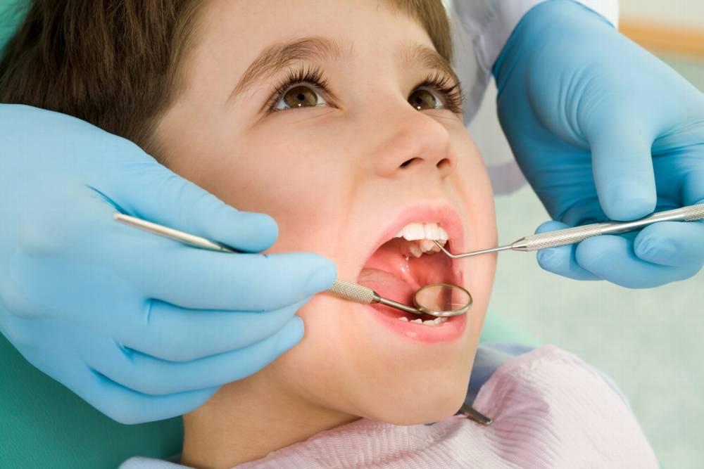 Close-up of little boy opening his mouth wide during inspection of oral cavity